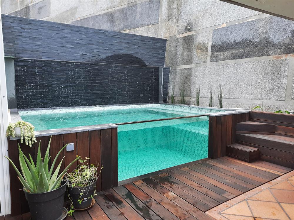 Piscina elevada junto a deck e jardim